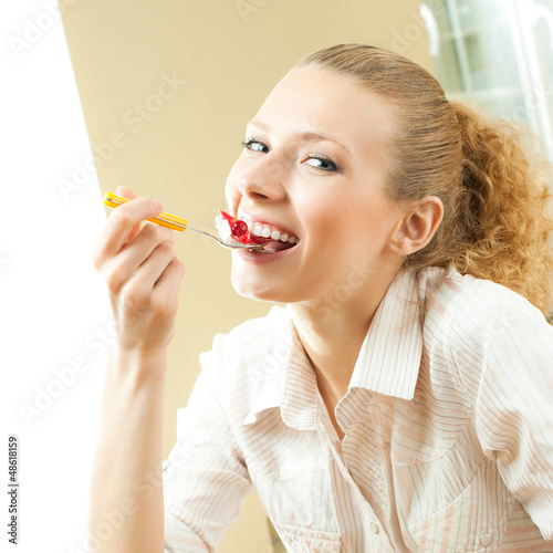 Photo: Cheerful blond young woman eating torte Cheerful blond young woman eating torte