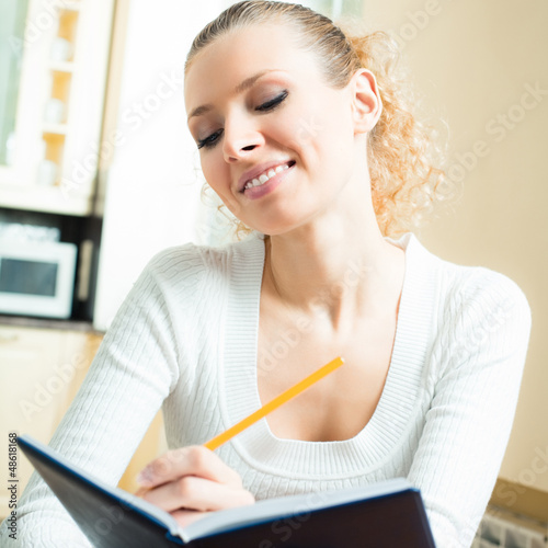 Photo: Young woman studying with notebook, indoors Young woman studying with notebook, indoors