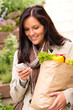 Smiling woman shopping vegetables mobile phone sms