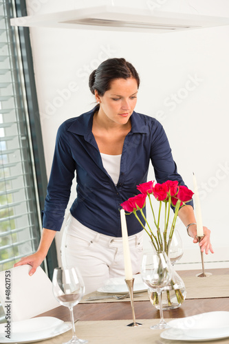 Photo: Young woman placing candle table roses romantic Young woman placing candle table roses romantic
