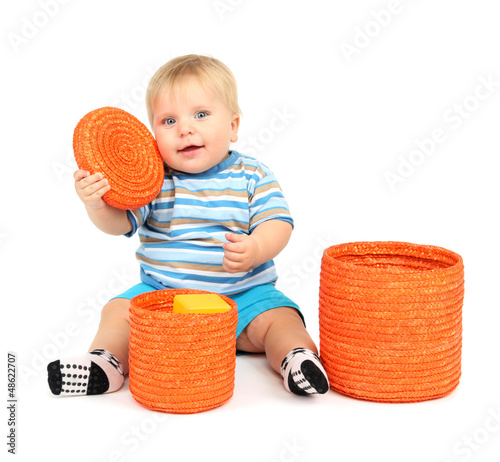 Photo: Little boy playing with color wicker boxes, isolated on white Little boy playing with color wicker boxes, isolated on white