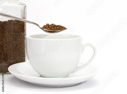 Photo: Spoon of instant coffee granules with cup and saucer and jar Spoon of instant coffee granules with cup and saucer and jar