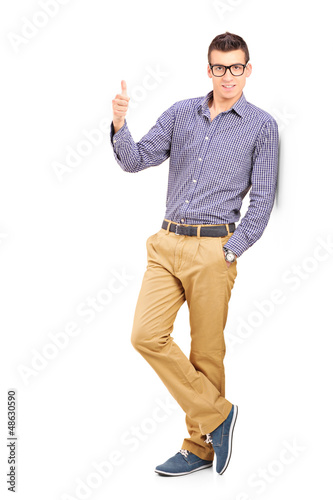 Photo: Full length portrait of a young man giving a thumb up Full length portrait of a young man giving a thumb up