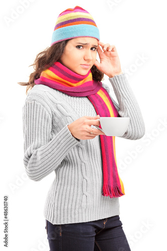 Photo: Young female having a headache and holding a cup of tea Young female having a headache and holding a cup of tea