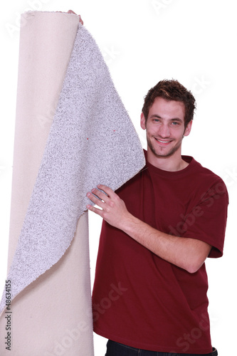 Photo: Young man standing with roll of carpet Young man standing with roll of carpet