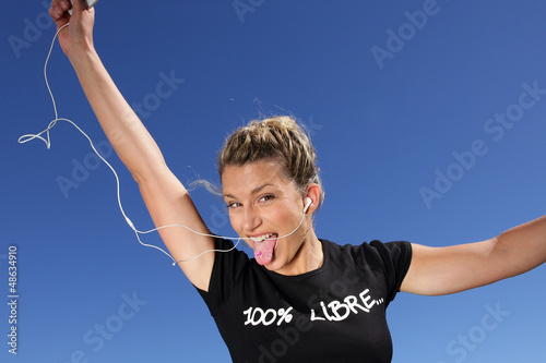 Photo: Funny woman listening to music outdoors through digital player Funny woman listening to music outdoors through digital player