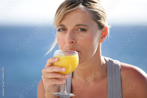 Photo: Woman drinking a glass of orange juice Woman drinking a glass of orange juice