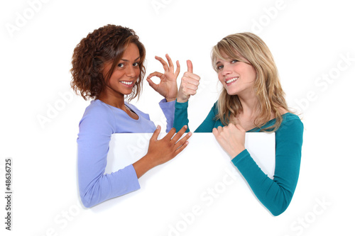 Photo: Satisfied girls behind white board Satisfied girls behind white board