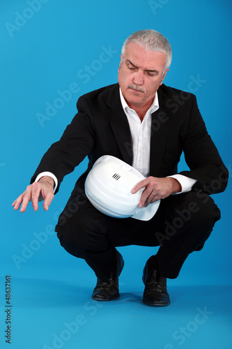 Photo: senior businessman holding a helmet senior businessman holding a helmet