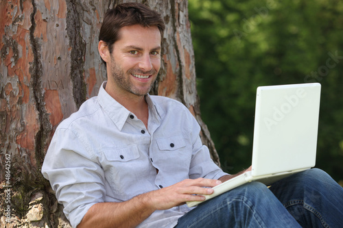 Photo: Man using laptop outside Man using laptop outside