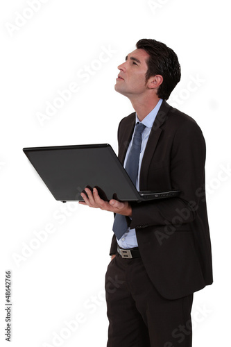 Photo: Businessman looking upwards and holding a laptop Businessman looking upwards and holding a laptop