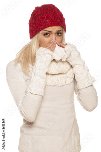 Photo: cold girl with a red winter hat wipes his nose with a tissue cold girl with a red winter hat wipes his nose with a tissue