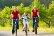 Family With Kid Cycling In Sum...
