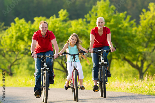 Photo: Family with kid cycling in summer with bicycles Family with kid cycling in summer with bicycles