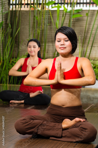 Photo: Asian women doing yoga in tropical setting Asian women doing yoga in tropical setting