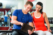woman and Personal Trainer in gym, with dumbbells