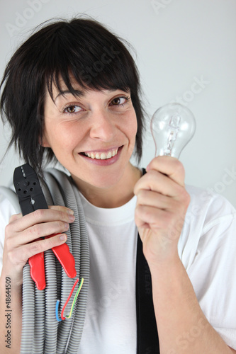Photo: Female electrician holding replacement wiring and bulb Female electrician holding replacement wiring and bulb