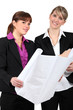 Two women holding plans