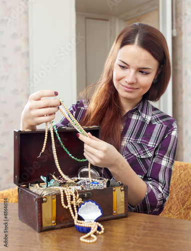 Photo: pretty girl chooses jewelry in treasure chest pretty girl chooses jewelry in treasure chest