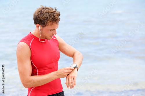 Photo: Athlete runner looking at heart rate monitor watch Athlete runner looking at heart rate monitor watch