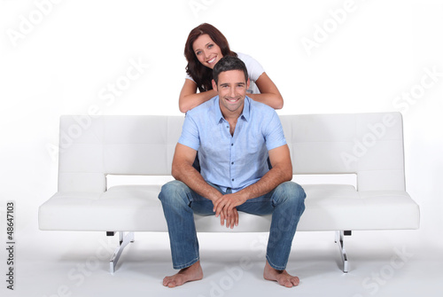 Photo: Smiling couple on a sofa, studio shot Smiling couple on a sofa, studio shot