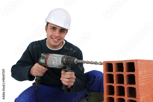 Photo: Man drilling hole in aerating brick Man drilling hole in aerating brick
