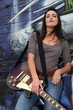 Cool female guitarist standing against graffiti