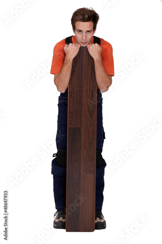 Photo: Man stood with plank of laminate flooring Man stood with plank of laminate flooring
