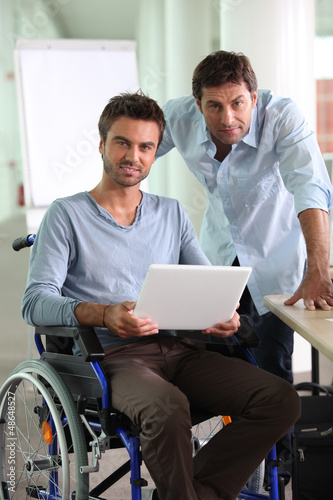 Photo: Man in wheelchair holding laptop Man in wheelchair holding laptop
