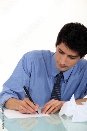 Photo: Frustrated man writing at desk Frustrated man writing at desk