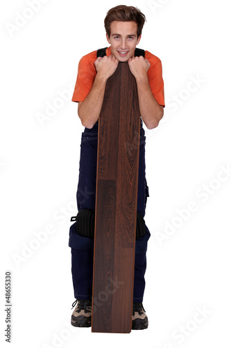 Photo: young handyman with a floorboard young handyman with a floorboard