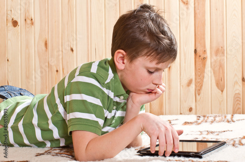 Photo: teenager boy lying on the bed with a Tablet PC teenager boy lying on the bed with a Tablet PC