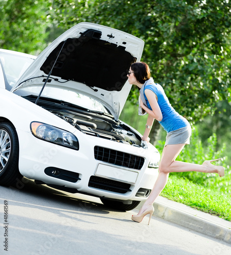 Photo: Woman opens car bonnet and tries to repair the broken car Woman opens car bonnet and tries to repair the broken car