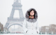 Photo: Beautiful girl in fur hood with the Eiffel tower in background Beautiful girl in fur hood with the Eiffel tower in background