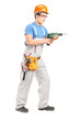 Photo: Full length portrait of a manual worker with helmet using a dril Full length portrait of a manual worker with helmet using a dril