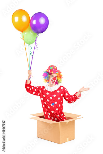 Photo: Male clown in a cardboard box holding bunch of balloons Male clown in a cardboard box holding bunch of balloons