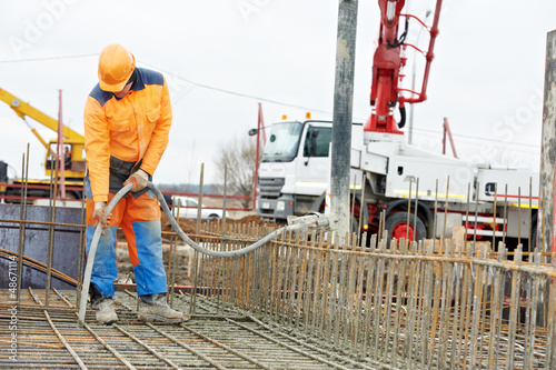 Photo: builder worker vibrating concrete in form builder worker vibrating concrete in form