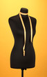 empty black mannequin with measuring tape  on orange background