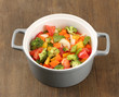Vegetable stew in gray pot on wooden background