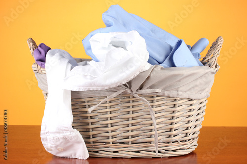 Photo: Bright clothes in laundry basket,on color background Bright clothes in laundry basket,on color background