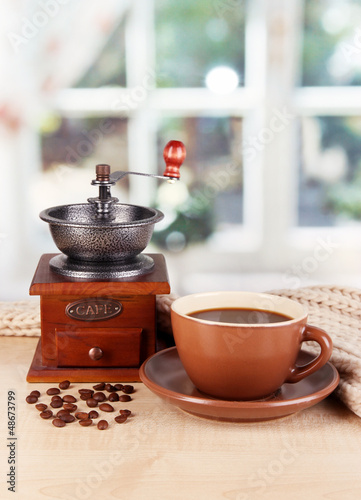 Photo: cup of coffee with scarf and coffee mill on table in room cup of coffee with scarf and coffee mill on table in room