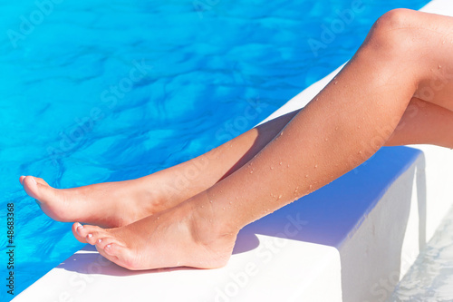 Photo: Sexy female legs at blue water of swimming pool Sexy female legs at blue water of swimming pool