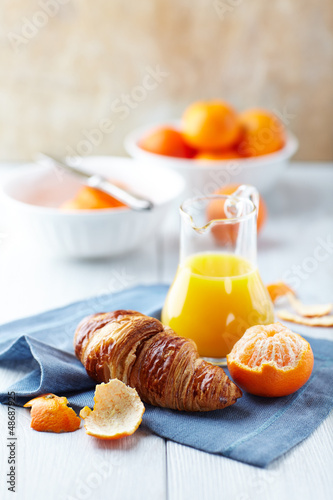 Photo: Croissant, mandarins and mandarin juice on kitchen table Croissant, mandarins and mandarin juice on kitchen table