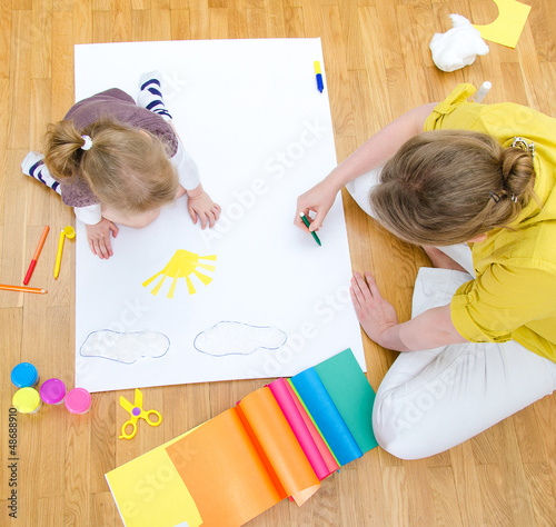 Photo: Young woman and little girl drawing. Top view Young woman and little girl drawing. Top view