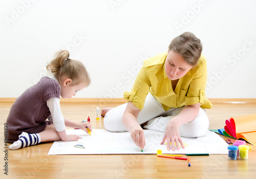 Photo: Young woman and little girl drawing together Young woman and little girl drawing together