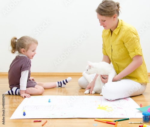 Photo: Young woman and little girl drawing together Young woman and little girl drawing together