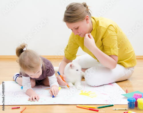 Photo: Young woman and little girl drawing together Young woman and little girl drawing together
