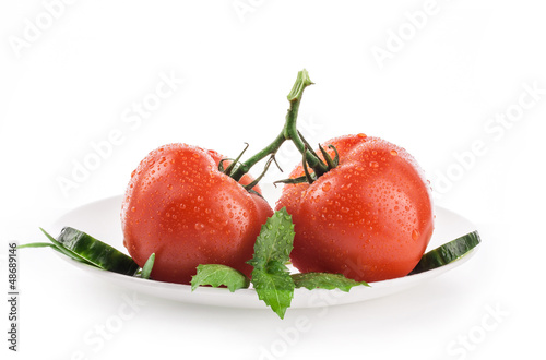 Photo: Tomatoes and basil on white plate, isolated on white background Tomatoes and basil on white plate, isolated on white background
