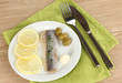 Dish of herring and lemon on plate on wooden table close-up