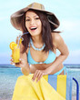 Photo: Girl in bikini drinking alcohol coctail through a straw. Girl in bikini drinking alcohol coctail through a straw.
